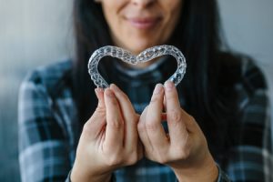 Patient Making a Heart Shape with Dental Aligners